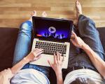a couple sat on a sofa with a laptop watching YouTube