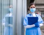 nurse in PPE holding a blue clipboard