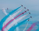 red arrows in the air with red, white and blue smoke trails behind them