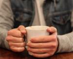 Person holding a cup containing a hot drink