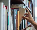 This image shows a person with books in a library