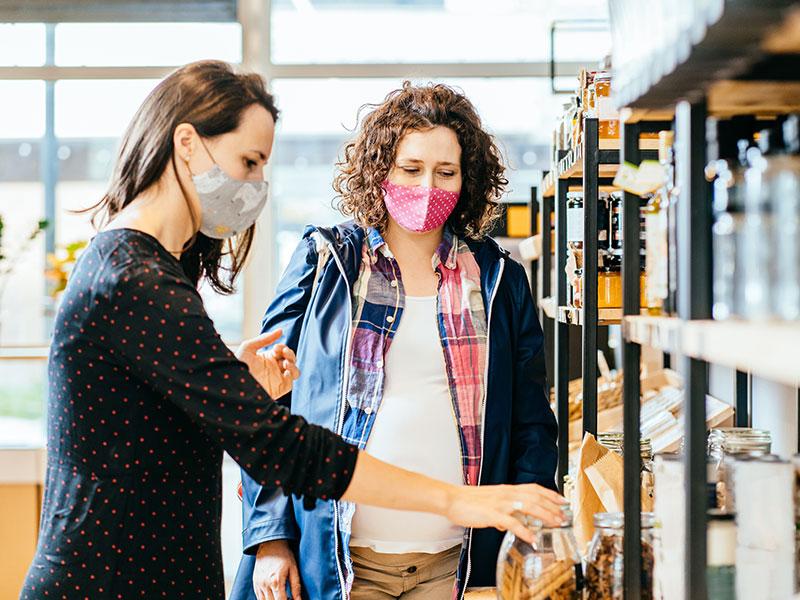 Two women wearing face masks while shopping