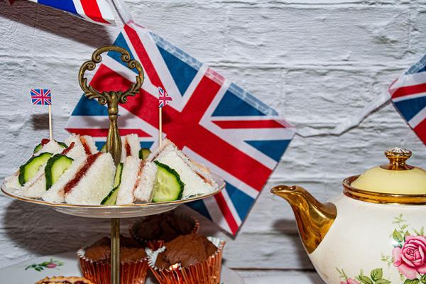 sandwiches on top of an afternoon tea stand with a Union flag in the background